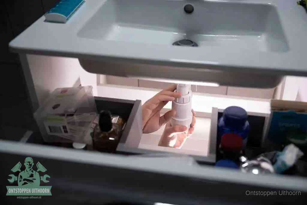 Een pompfles met zeep boven een wastafel, de heet water en afwasmiddel-methode om een vetprop in de afvoer los te maken in Uithoorn