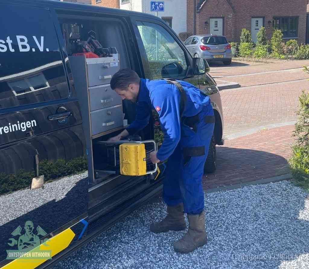 Een monteur pakt buiten op de oprit gereedschap uit de bedrijfsbus, het moment om een professional in te schakelen voor een verstopte afvoer in Uithoorn