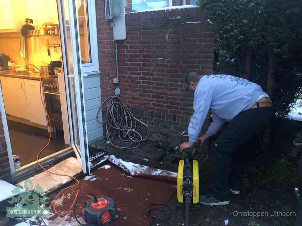 Een monteur werkt buiten bij een open riool-/grondput met een elektrische ontstoppingsmachine om een verborgen afvoerprobleem op te sporen in Uithoorn