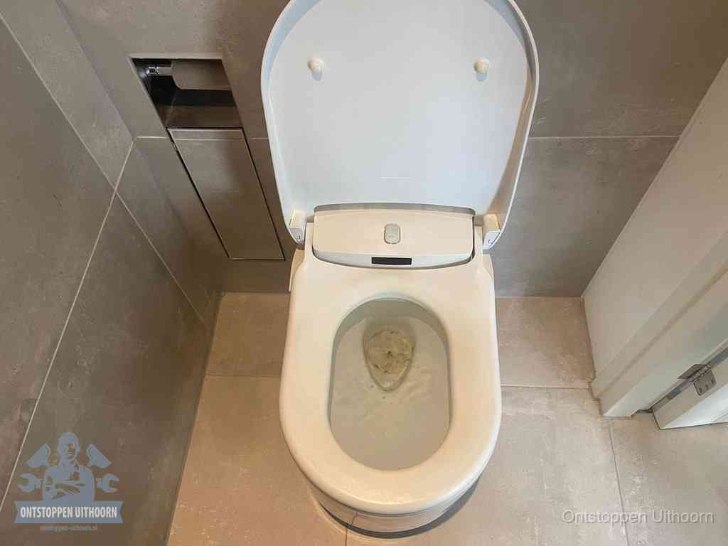 Een wit hangtoilet waarin een prop wc-papier op het water blijft drijven, een duidelijk signaal van een verstopte wc in Uithoorn