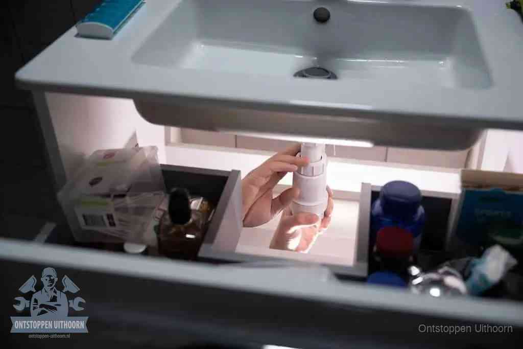 Een pompfles met zeep boven een wastafel in de toiletruimte, de warm water en afwasmiddel-methode om de wc te ontstoppen in Uithoorn